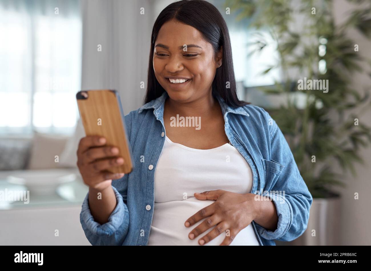 Ich Frage mich, ob die Leute wissen, wie sehr mir ihre guten Wünsche bedeuten. Eine Schwangere benutzt ihr Handy, während sie zu Hause sitzt. Stockfoto
