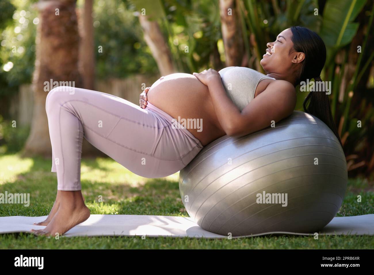 Ich möchte mich fit und stark für die Geburt fühlen. Eine Schwangere arbeitet draußen mit einem Stabilitätsball. Stockfoto