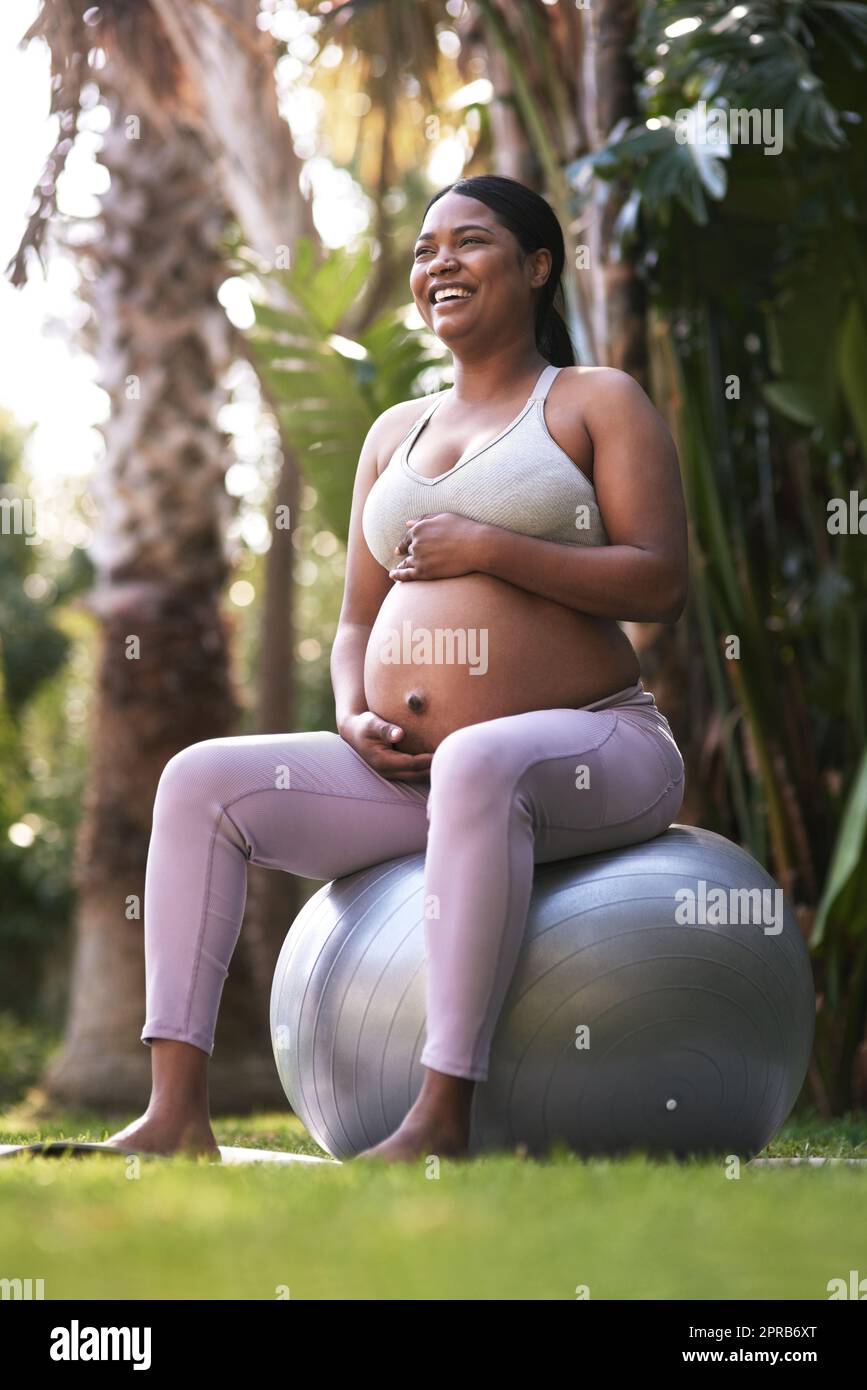 Mein Baby ist genauso aktiv wie ich. Eine Schwangere sitzt draußen auf einem Stabilitätsball. Stockfoto