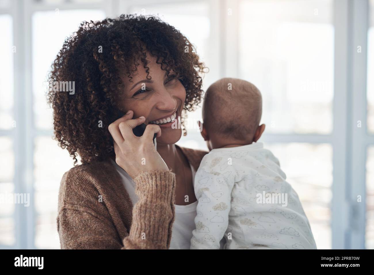 Wed Love to Bis zum nächsten Mal. eine junge Frau, die ein Smartphone benutzt, während sie ihr entzückendes Mädchen zu Hause trägt. Stockfoto