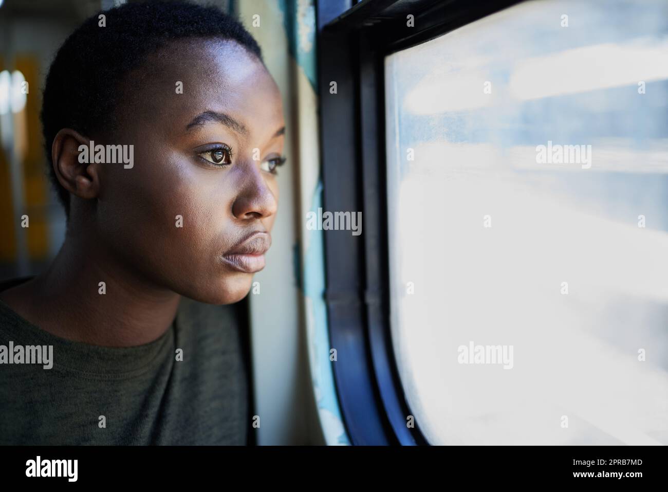 Eine junge Frau, die deprimiert aus dem Fenster eines Zuges starrt. Stockfoto