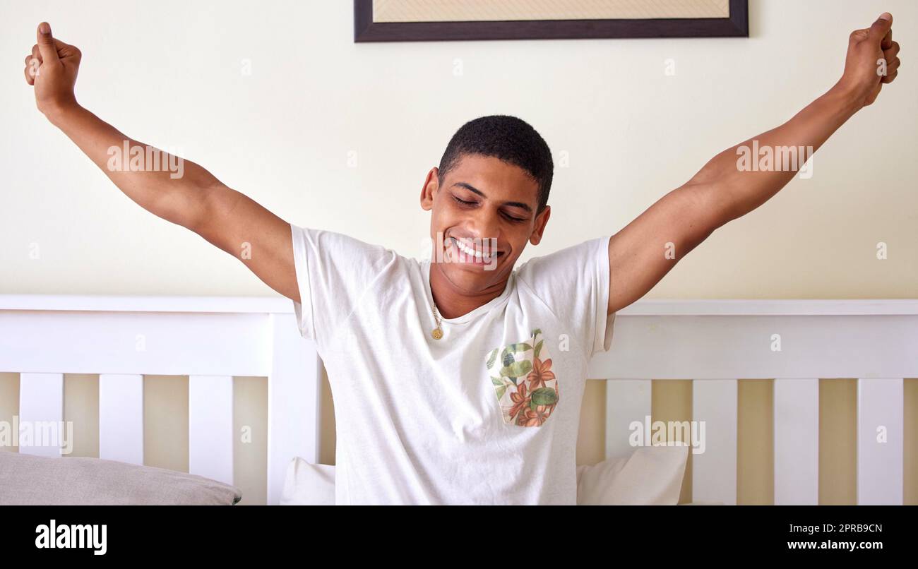 Erhebt euch und glänzt schlafend. Ein hübscher junger Mann sitzt im Bett und dehnt sich in den frühen Morgenstunden. Stockfoto