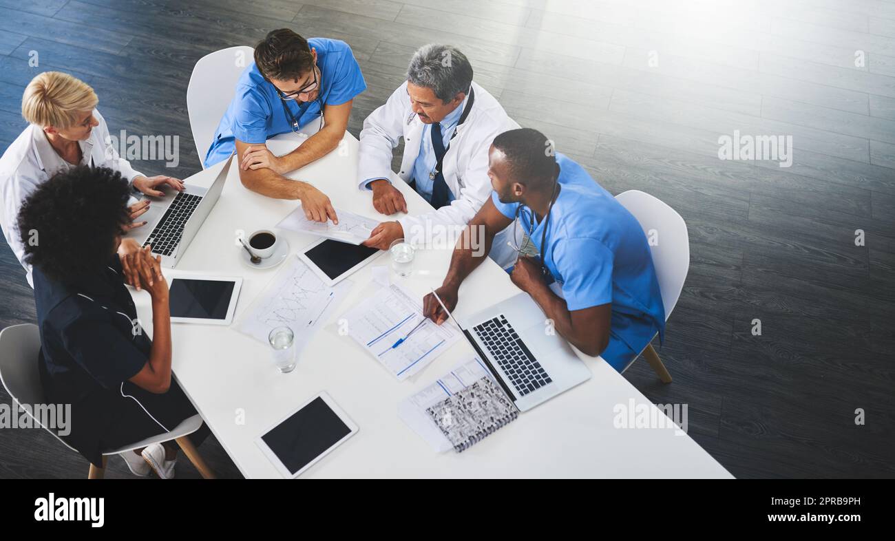 Team von medizinischen Arbeitern, die mit Laptops um den Tisch sitzen und sich treffen. Arzte und Mitarbeiter diskutieren Papiere und Testergebnisse. Gesundheitsexperten für tägliche Aufgaben und Aufgaben Stockfoto