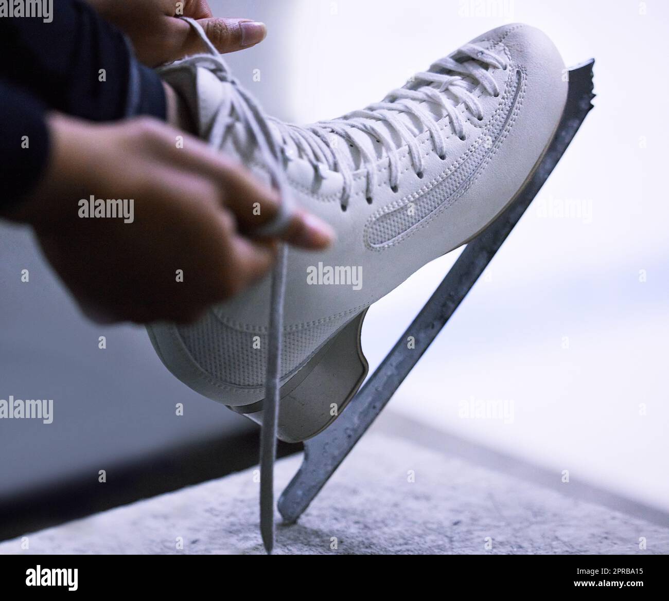 Schlittschuhe über Stilletos. Eine nicht erkennbare Figur Skater Band die Schnürsenkel auf ihre Schlittschuhe. Stockfoto
