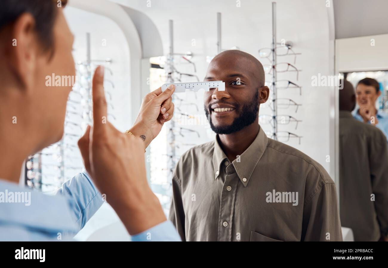 Hochwertige Augenpflege, die die Kunden immer wieder zurückbringt. Eine Optiker untersucht die Augen ihrer Patienten mit einem pd-Lineal. Stockfoto