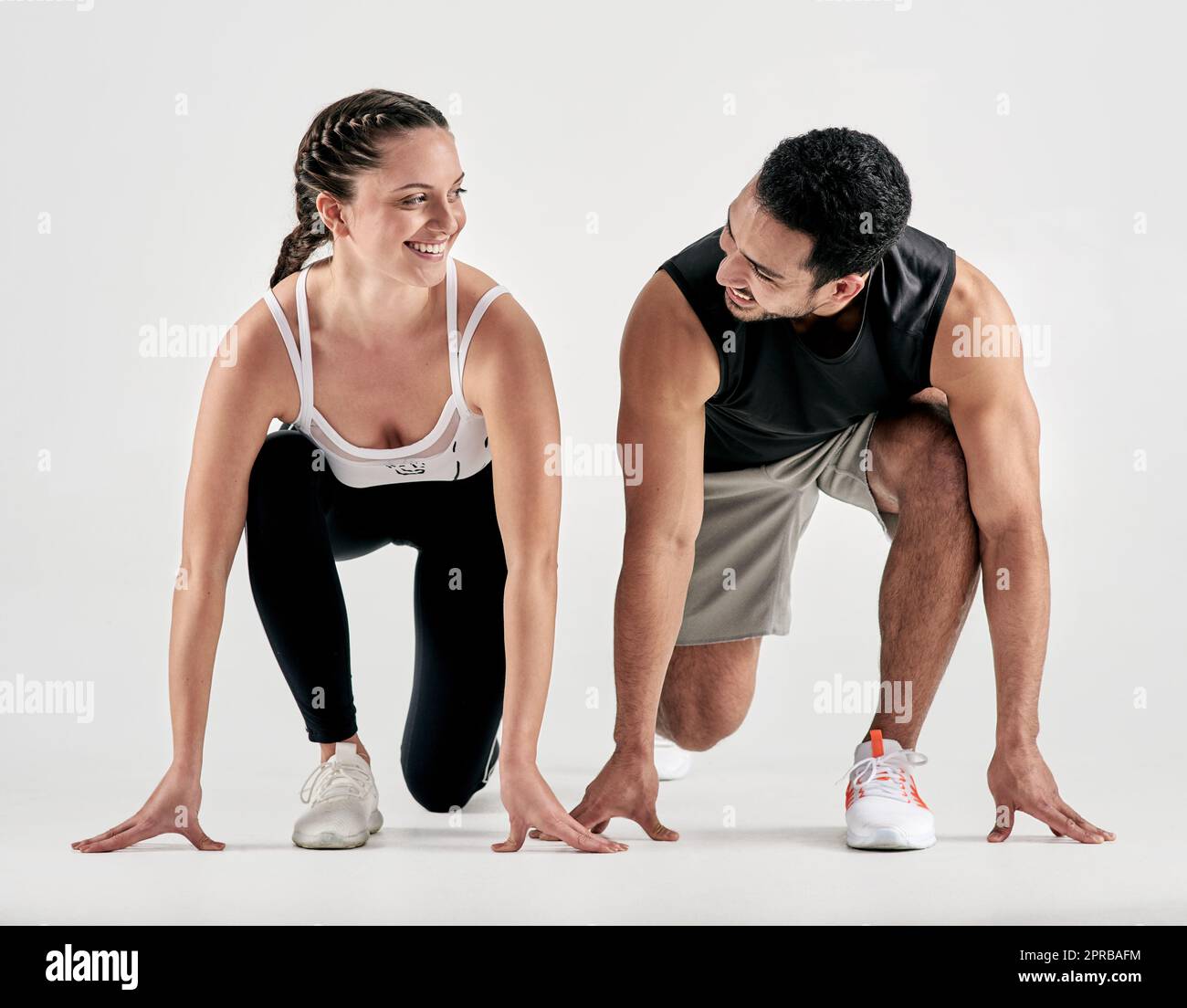 Dein Rennen, dein Tempo. Studioaufnahme eines sportlichen jungen Mannes und einer jungen Frau in Startposition vor weißem Hintergrund. Stockfoto