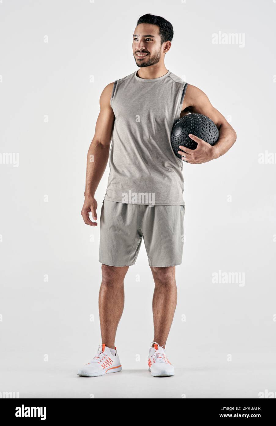 Ich bin stolz darauf, wie weit ich gekommen bin. Studioaufnahme eines muskulösen jungen Mannes, der einen Übungsball vor einem weißen Hintergrund hält. Stockfoto