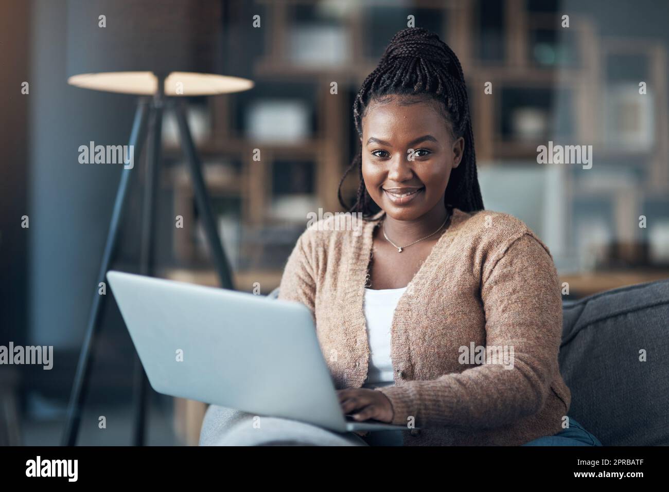 Jede Zeit ist Filmzeit. Eine attraktive junge Frau, die allein in ihrem Wohnzimmer sitzt und ihren Laptop benutzt. Stockfoto