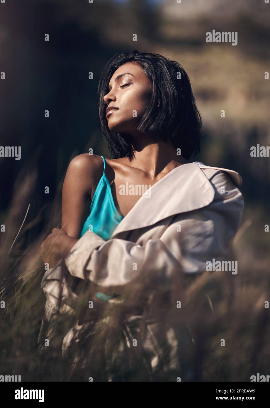 Ich liebe das Gefühl der Sonne auf meiner Haut. Eine modische junge Frau posiert im Freien. Stockfoto