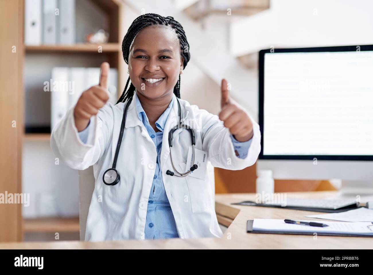 Es ist eine so erfüllende und lohnende Karriere für mich. Porträt einer jungen Ärztin, die in ihrem Büro Daumen nach oben zeigt. Stockfoto