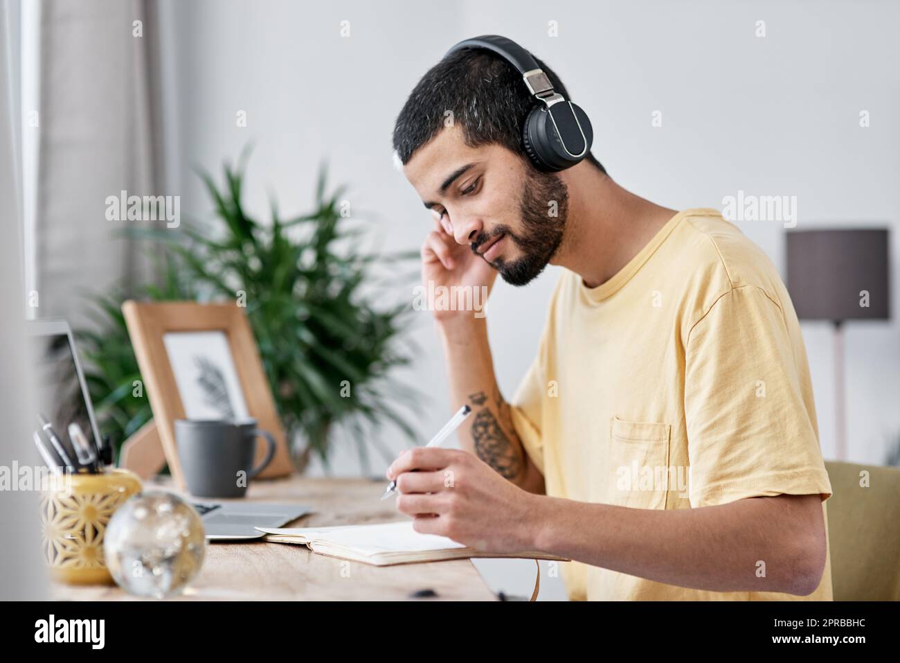 Kein Lärm, Kein Problem. ein junger Mann, der einen Laptop und Kopfhörer benutzt, während er von zu Hause aus arbeitet. Stockfoto
