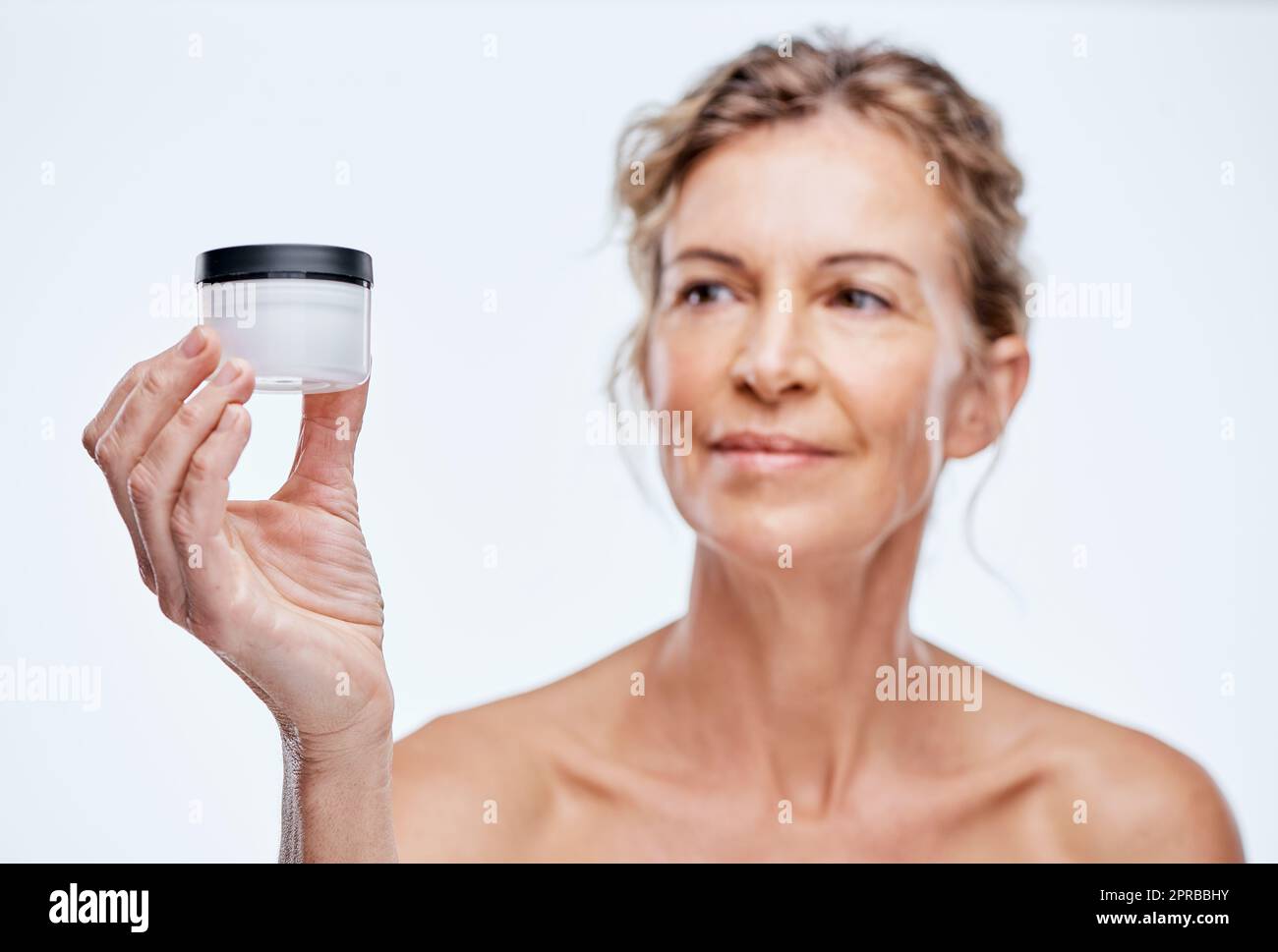 Es gibt nur ein Produkt, das für mich funktioniert. Eine reife Frau hält ein Beauty-Produkt vor einer Weile Hintergrund. Stockfoto