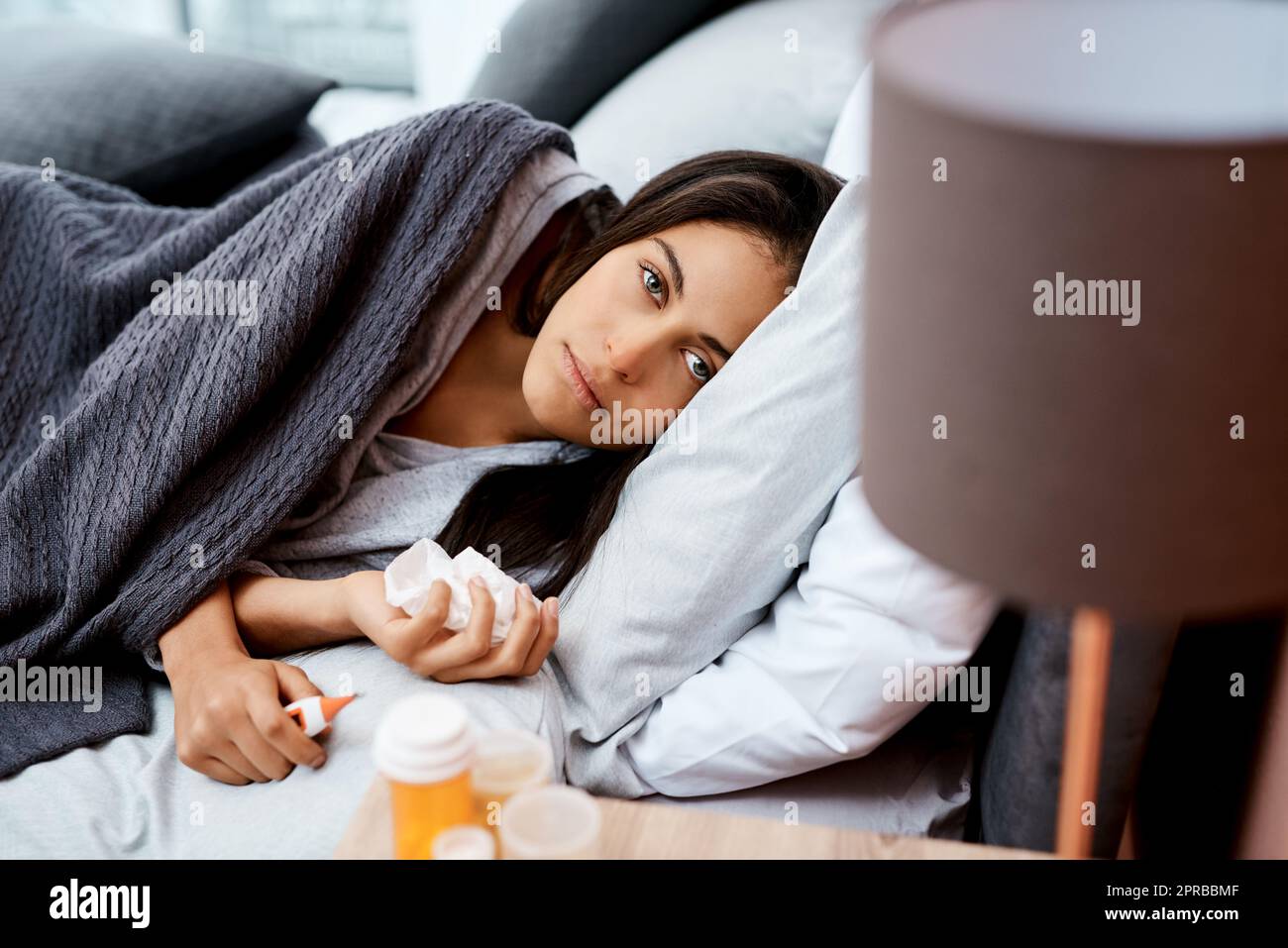 Schlagen Sie die Grippe, indem Sie im Bett bleiben. Eine junge Frau erholt sich von einer Krankheit im Bett zu Hause. Stockfoto