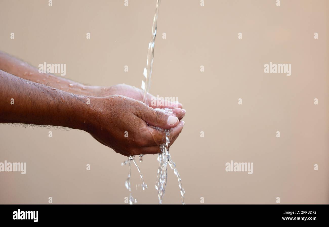 Wasser ist die treibende Kraft der Natur, des Lebens, der Existenz. Ein unkenntlich männlicher wäscht sich unter einem Wasserstrom draußen die Hände. Stockfoto