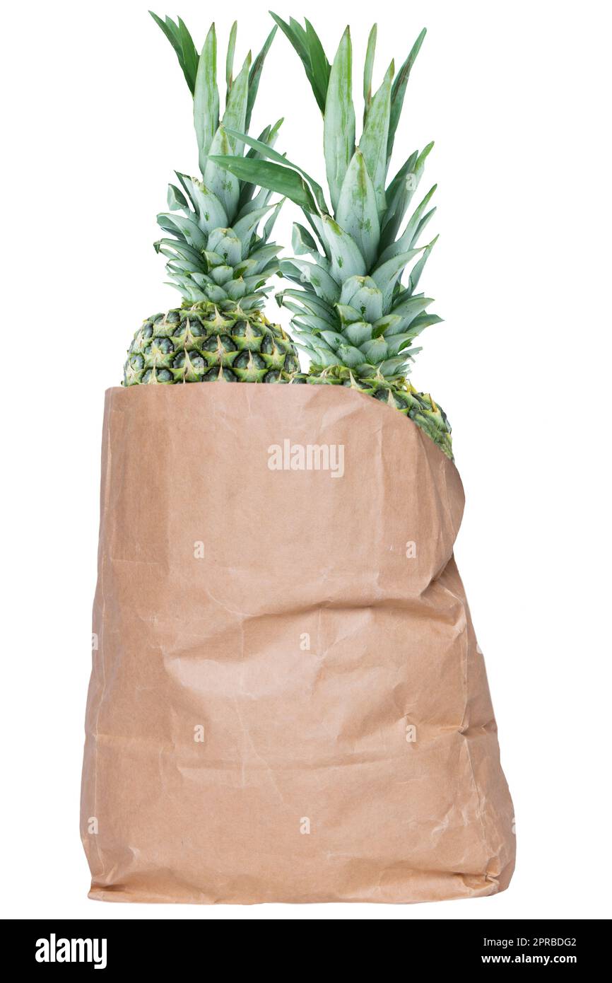 Nahaufnahme einer braunen Einkaufstasche aus Papier mit frischen, reifen Ananasfrüchten, isoliert auf weißem Hintergrund. Konzept der Stärkung des Immunsystems. Gesunde Ernährung. Tropische Früchte. Stockfoto