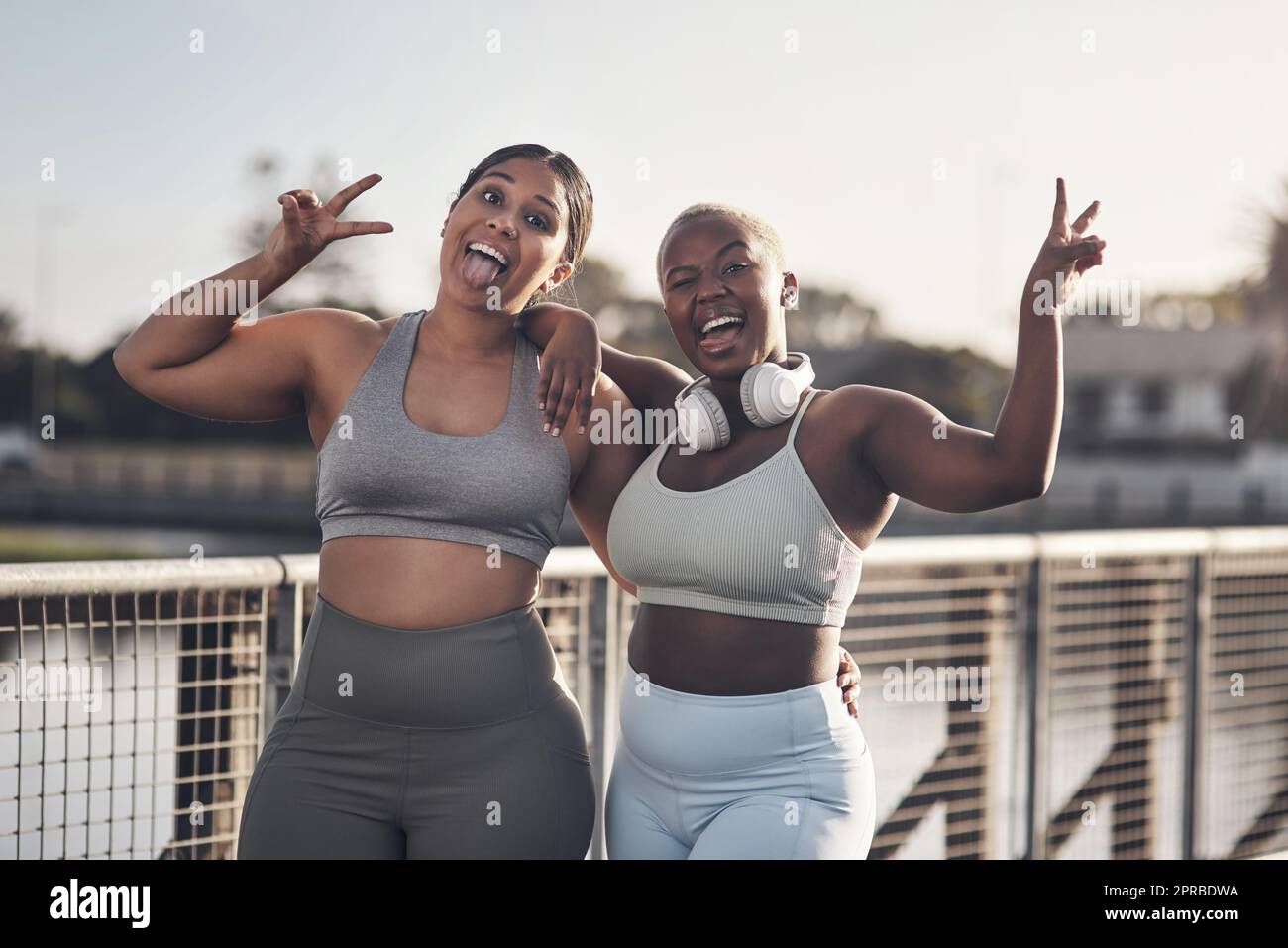 Trainieren Sie für ein besseres Leben. Zwei junge Frauen zeigen die Friedensgeste, während sie zum Training unterwegs sind. Stockfoto