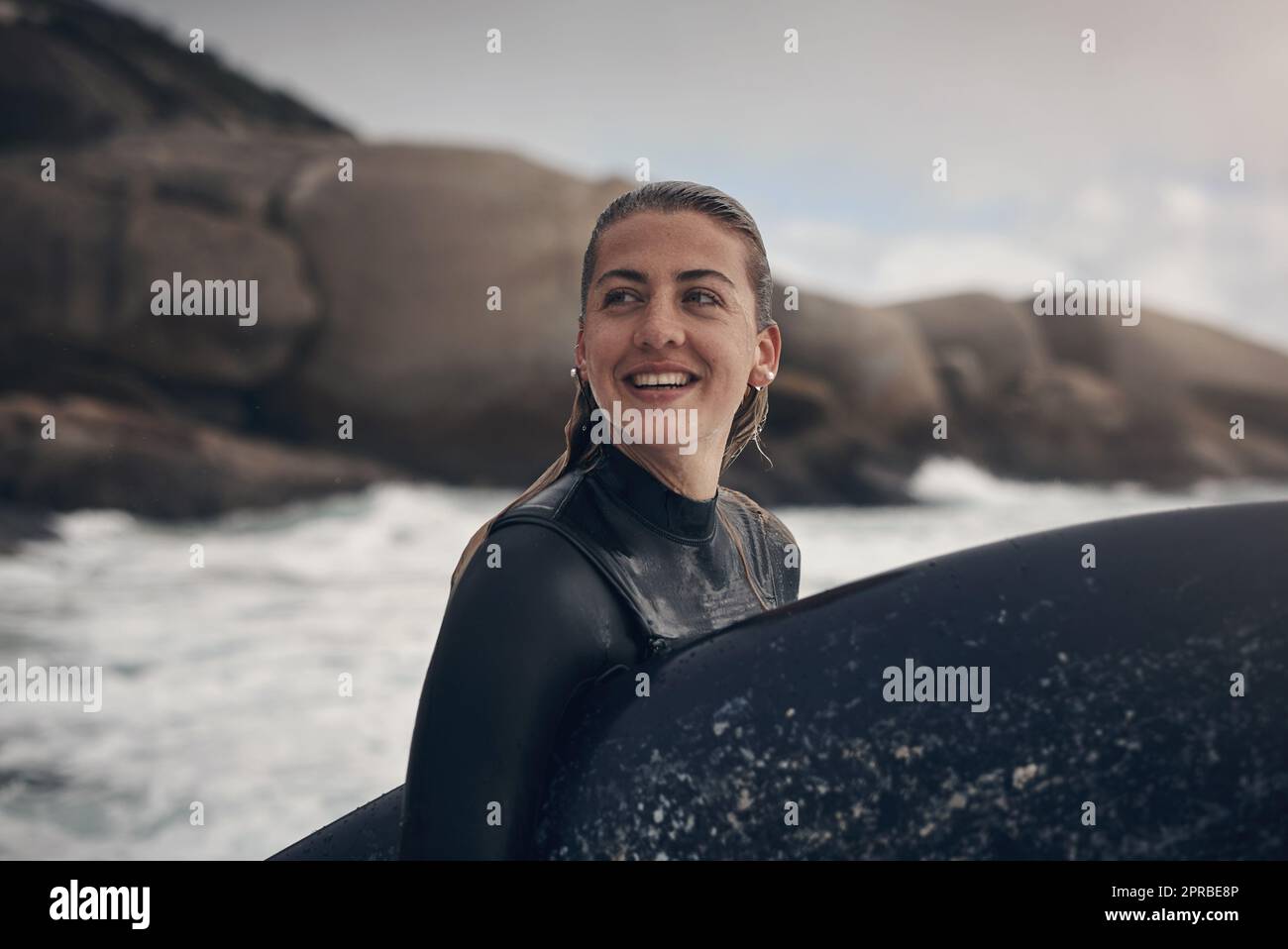 Surfen umgibt Sie mit Schönheit. Eine junge Frau, die am Strand surft. Stockfoto