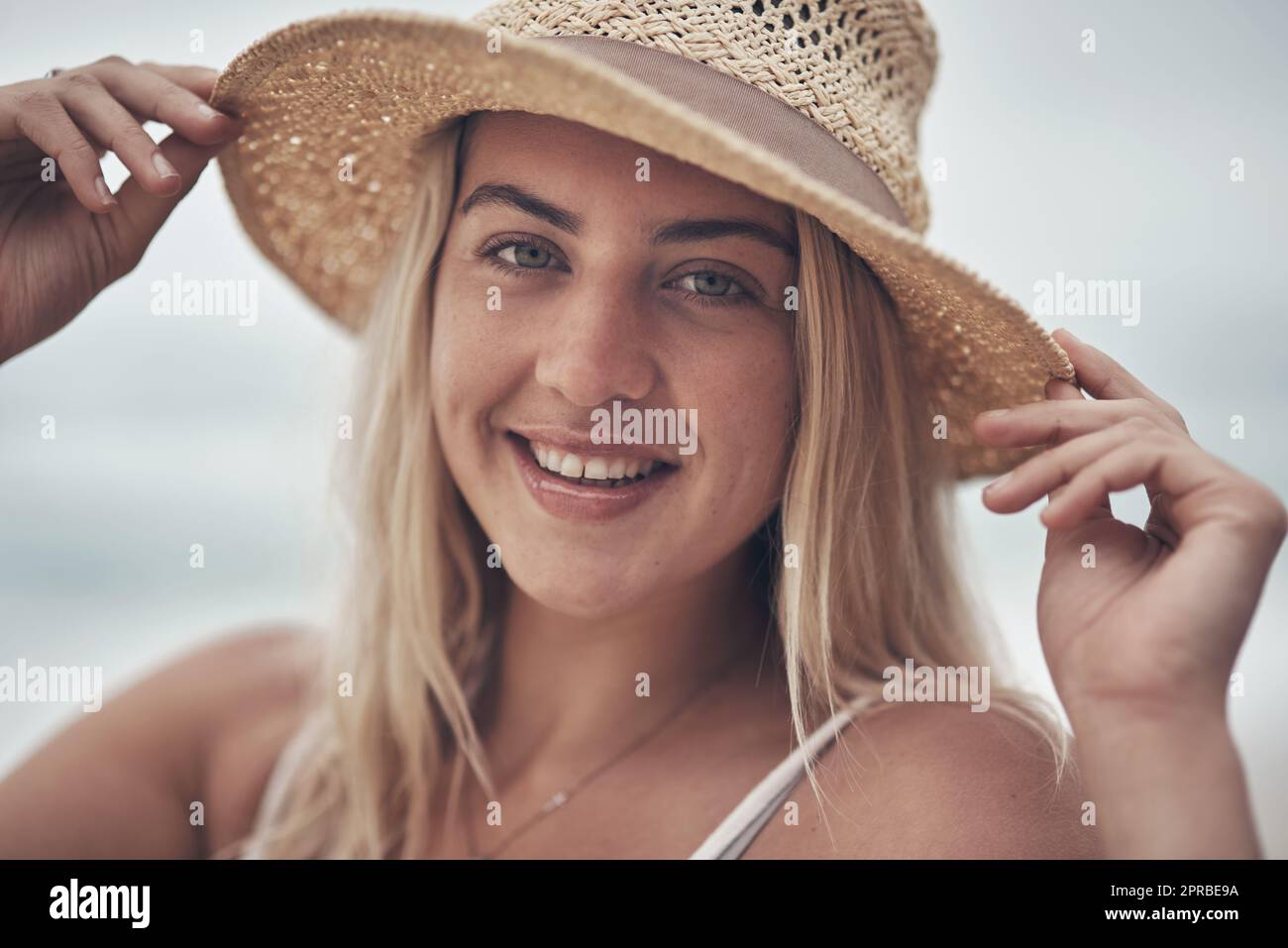 Ein guter Hut bringt mich in gute Laune. Eine schöne junge Frau, die den Tag am Strand verbringt. Stockfoto