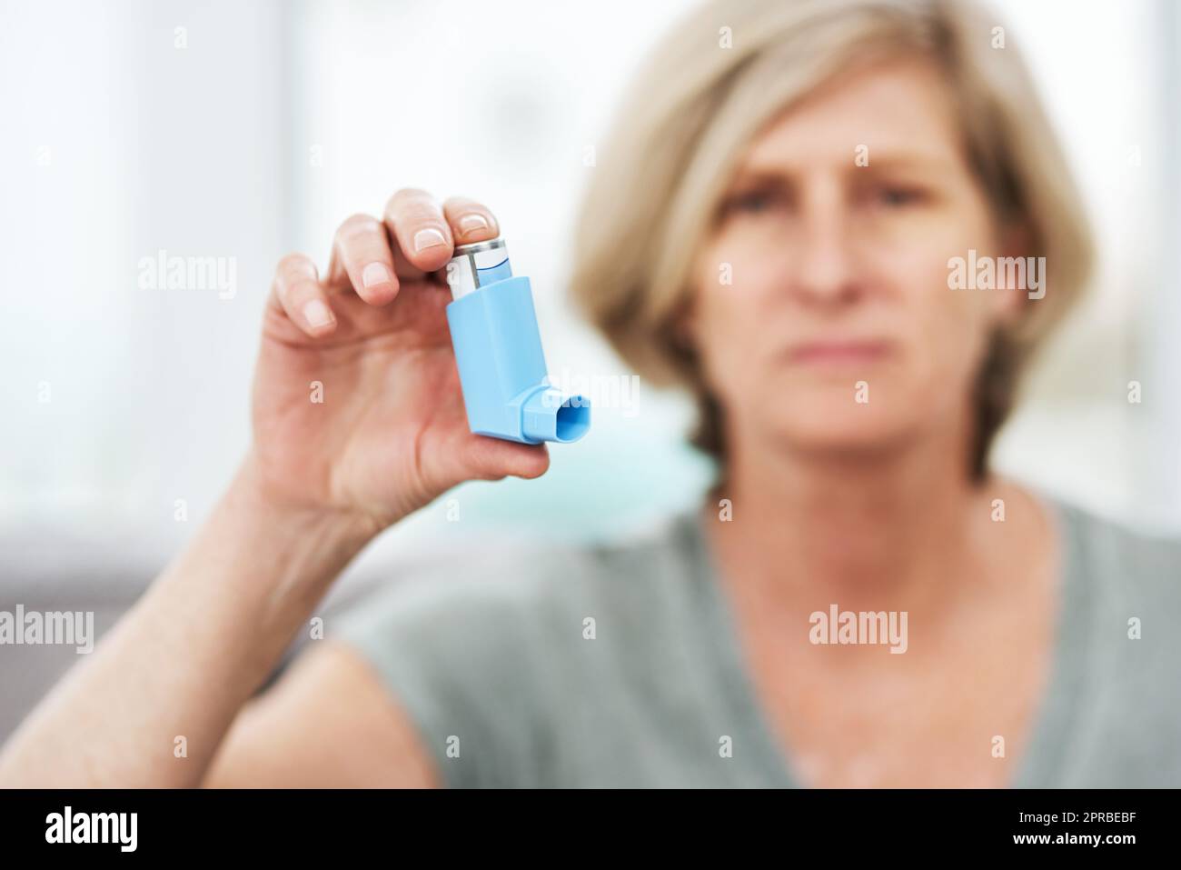 Ein Lebensretter, der in meine Hosentasche passt. Ein Senior, der zu Hause einen Asthmainhalator hält. Stockfoto