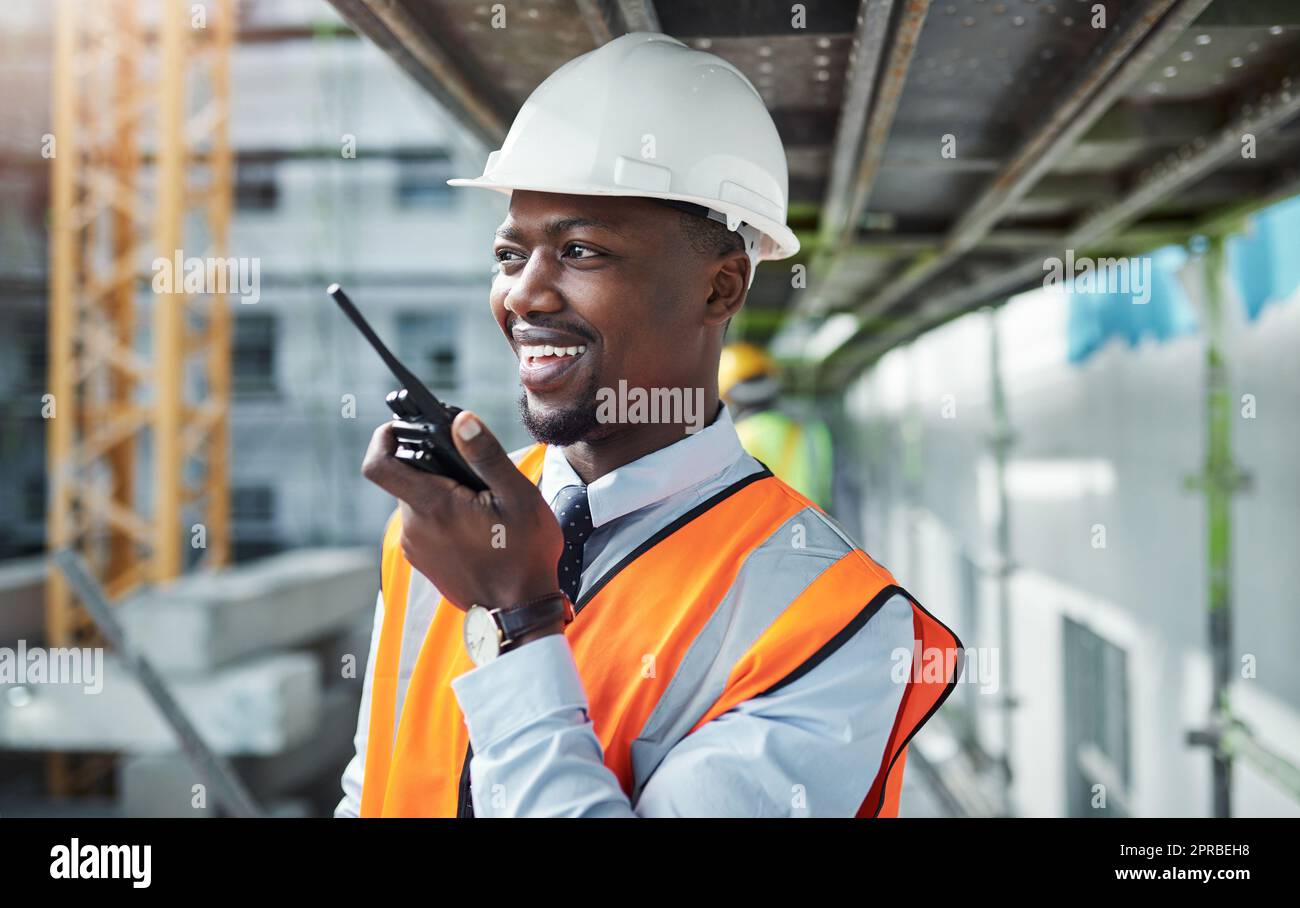 Kommunikation trägt ein Projekt von Anfang bis Ende. Ein junger Mann, der ein Walkie-Talkie benutzt, während er auf einer Baustelle arbeitet. Stockfoto