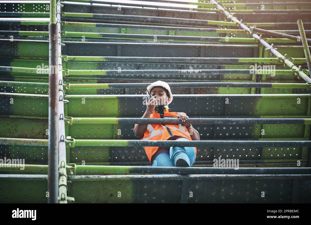 Als Projektmanagerin. Eine junge Frau, die auf einer Baustelle mit einem Walkie-Talkie arbeitet. Stockfoto