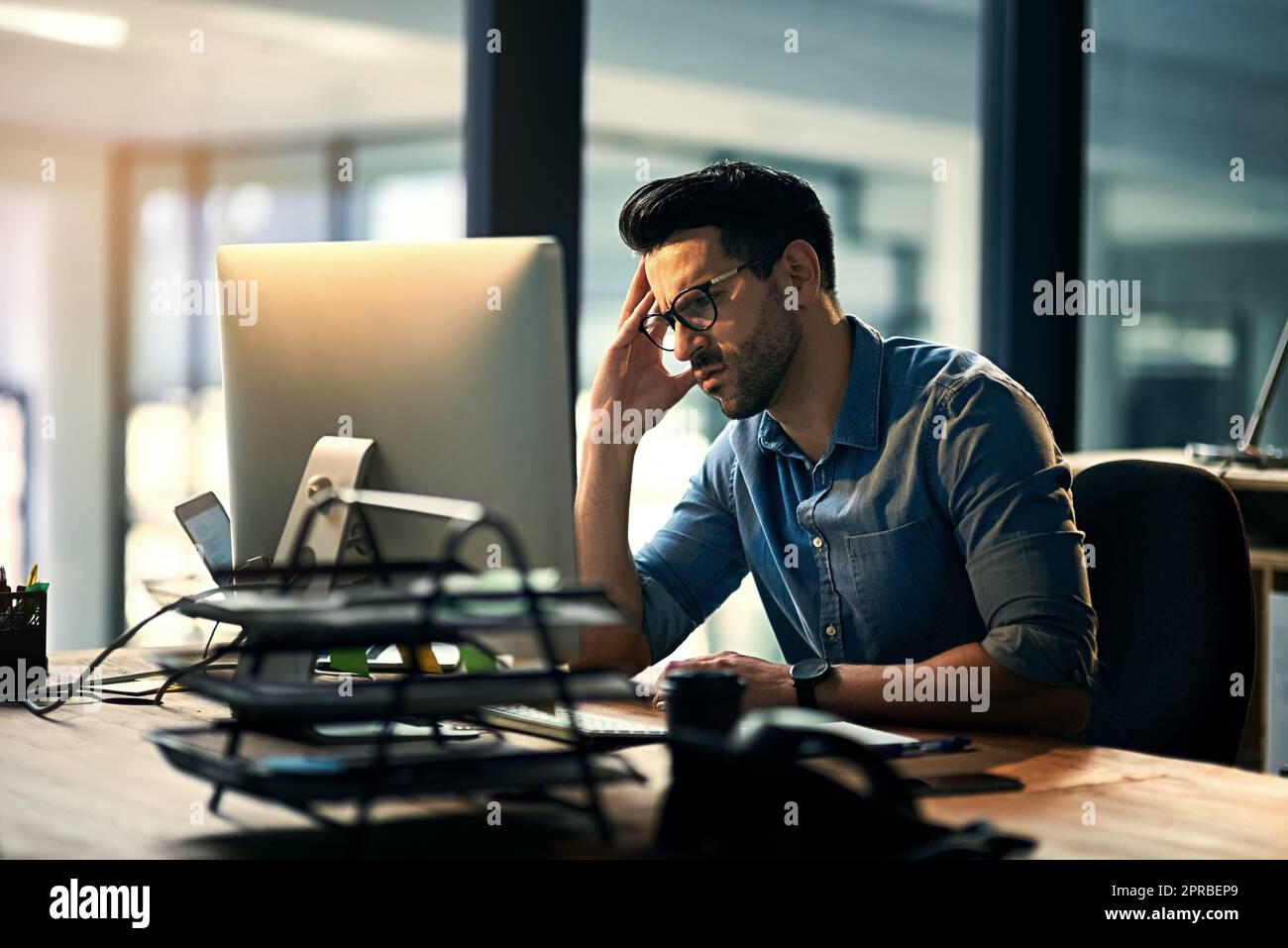 Geschäftsmann mit Stress, Kopfschmerzen, Müdigkeit, Schmerzen und Stress bei der Arbeit am Computer. Junger männlicher Büroangestellter arbeitet spät in der Nacht an einer Deadline. IT-Technologie-Typ sieht verärgert aus Stockfoto
