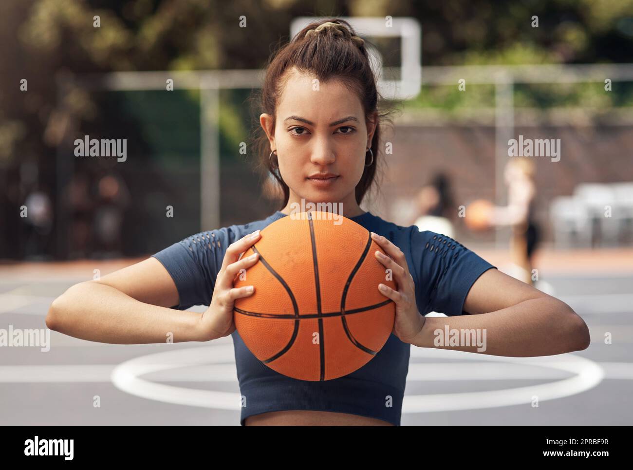 Um die Fähigkeiten zu gewinnen, braucht es Zeit und Geduld. Porträt einer sportlichen jungen Frau, die einen Basketball auf einem Sportplatz hält. Stockfoto