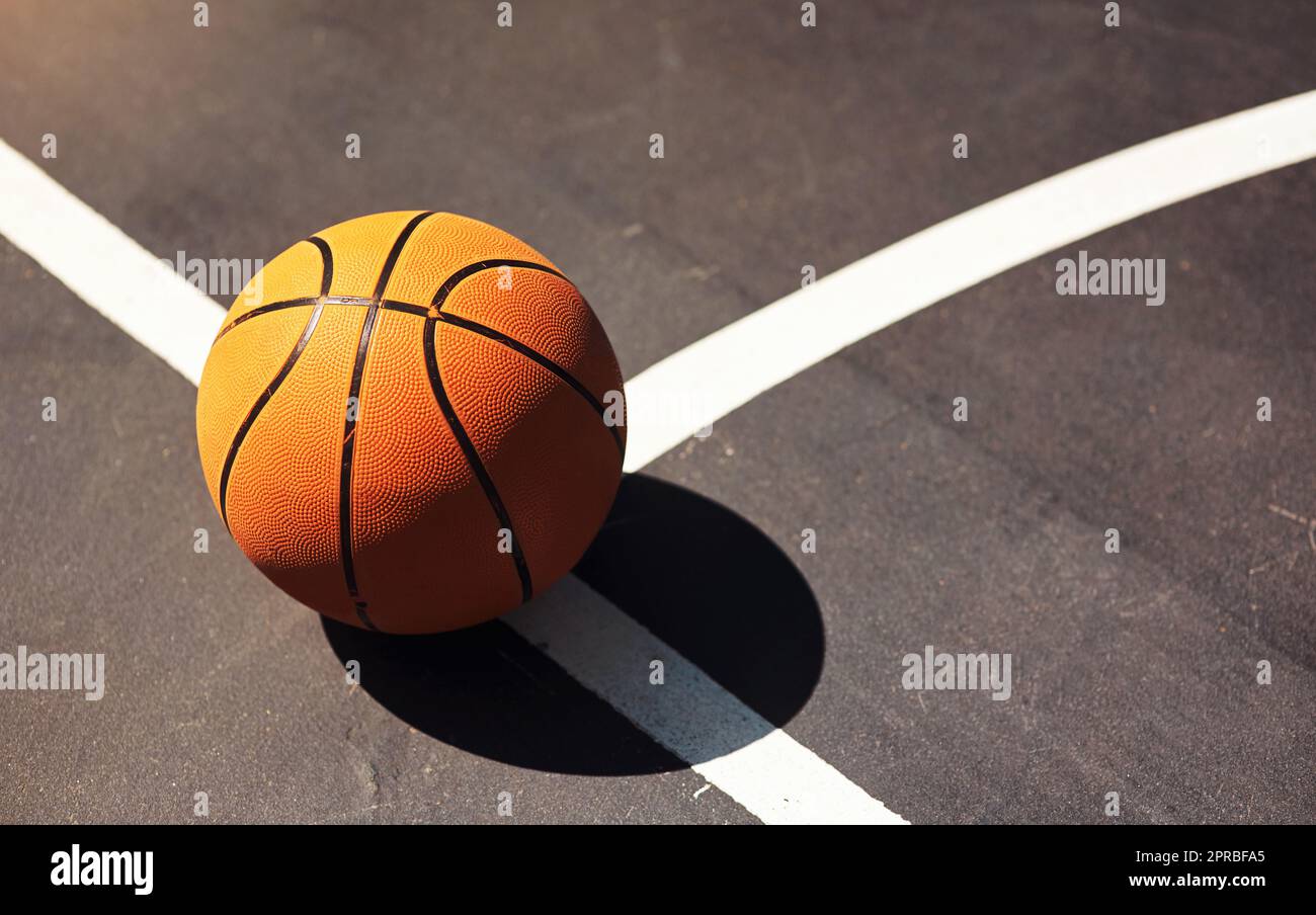 Zeit zum Abprallen und Schießen. Stillleben eines Basketballs auf dem Boden in einem Sportplatz. Stockfoto