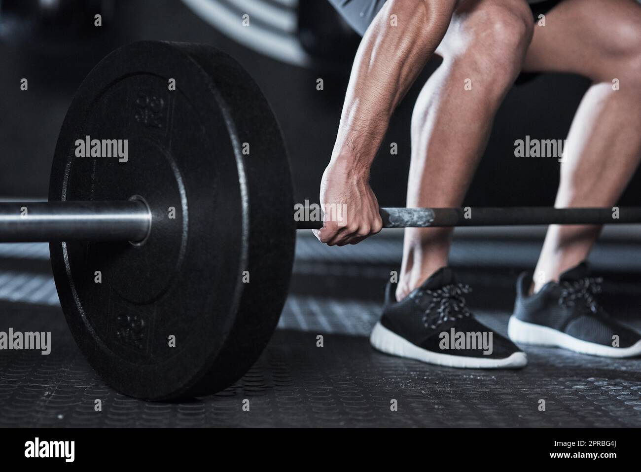 Ein unverkennbarer Mann, der während seines Trainings in einem Fitnessstudio eine Langhantel hebt. Stockfoto