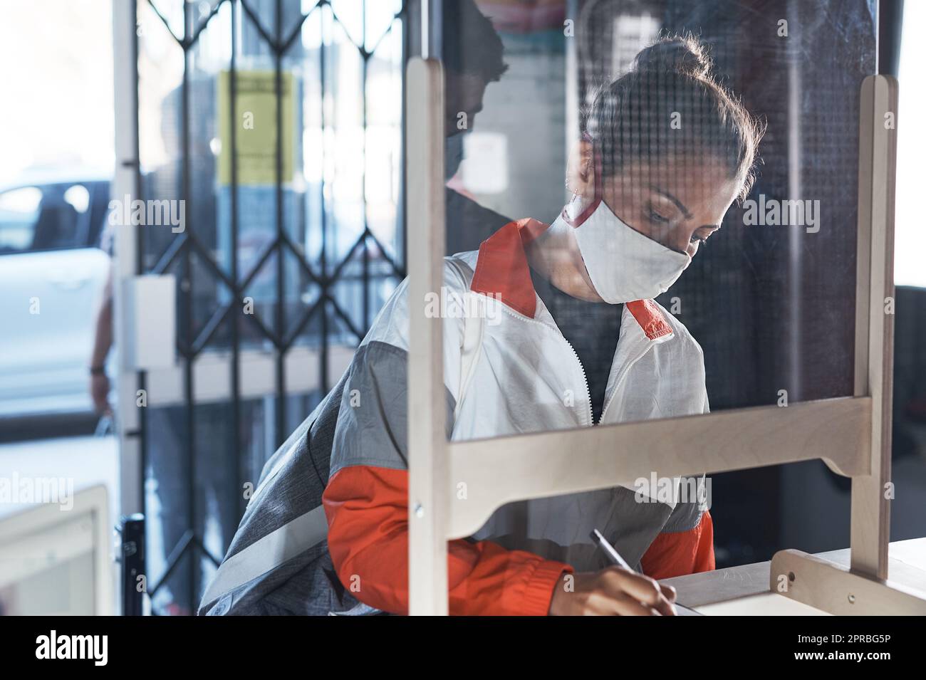 Eine junge Frau, die Papierkram an der Rezeption eines Fitnessstudios ausfüllt. Stockfoto