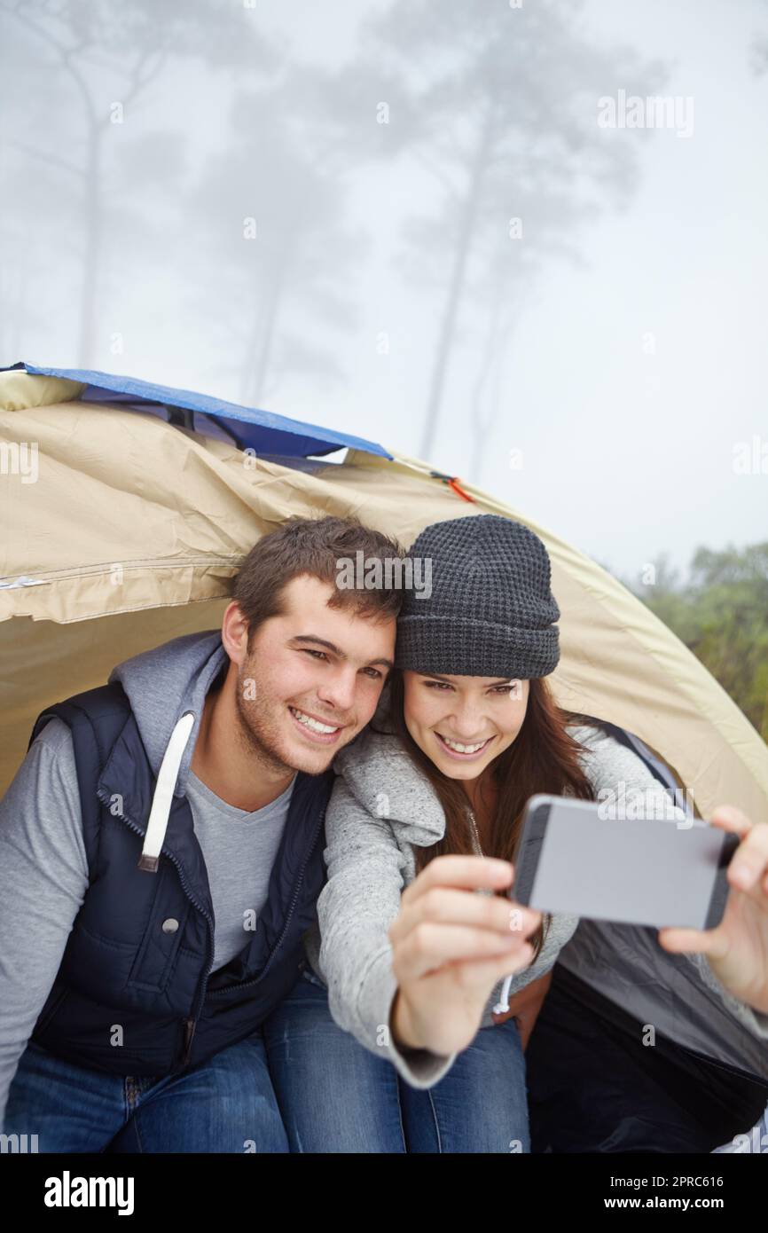 Schnappschuss eines Outdoor-Abenteuers. Ein junges Paar, das ein Foto von sich macht, während es in einem Zelt sitzt. Stockfoto