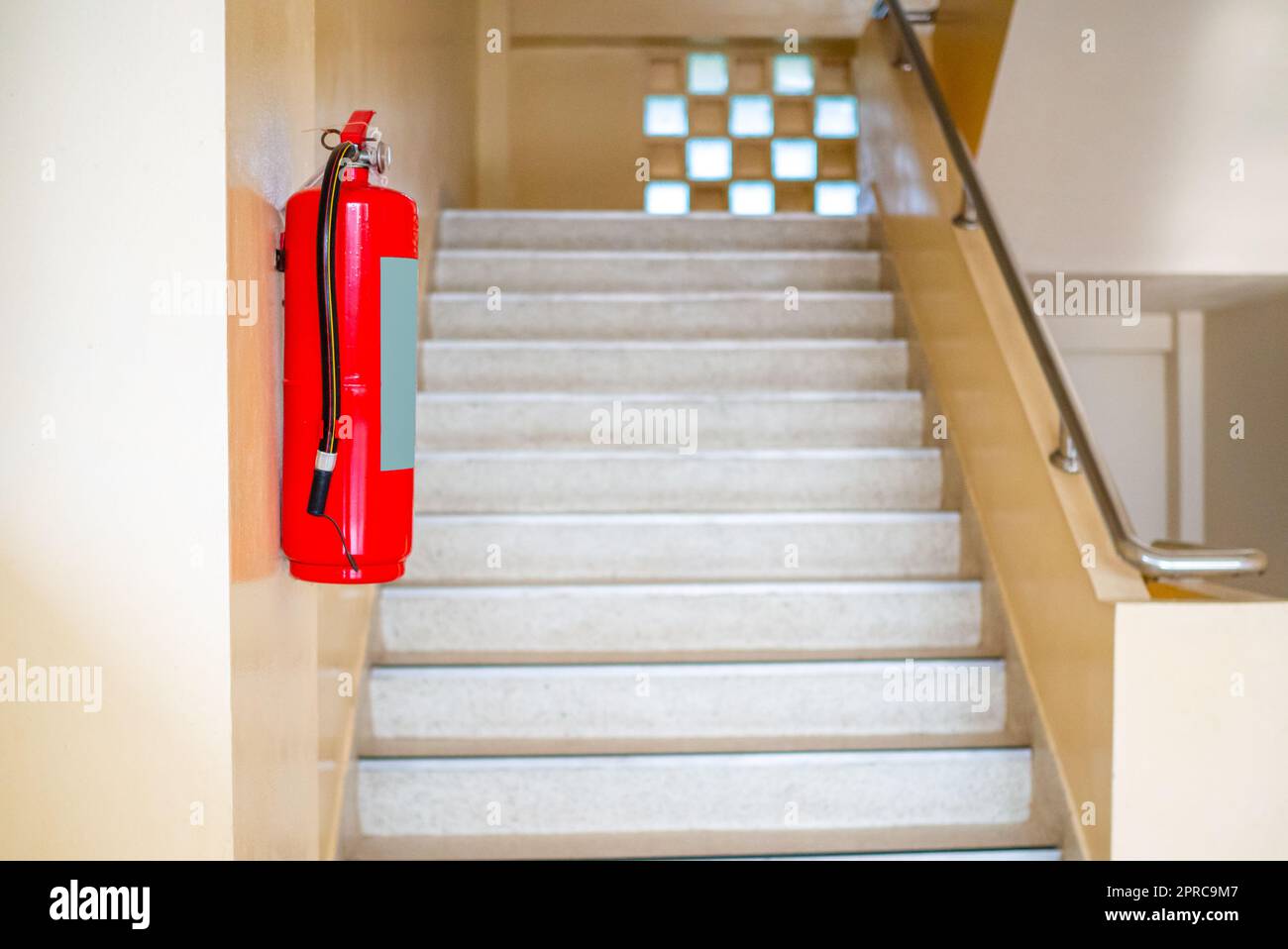 Ein Feuerlöscher hängt die Treppe hoch. Brandschutzkonzept. Stockfoto