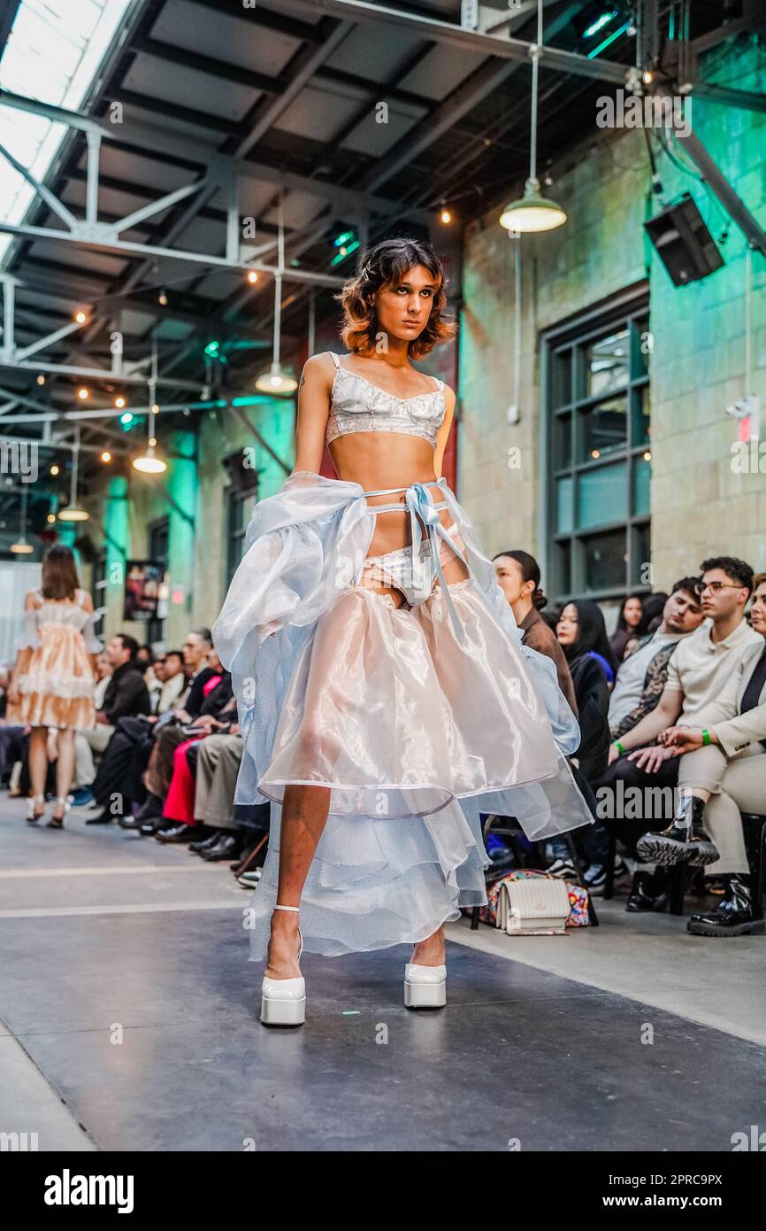 Männliches Kreuzkleid auf der Laufbahn als Model in einem weißen Kleid auf Plateauabsätzen Stockfoto