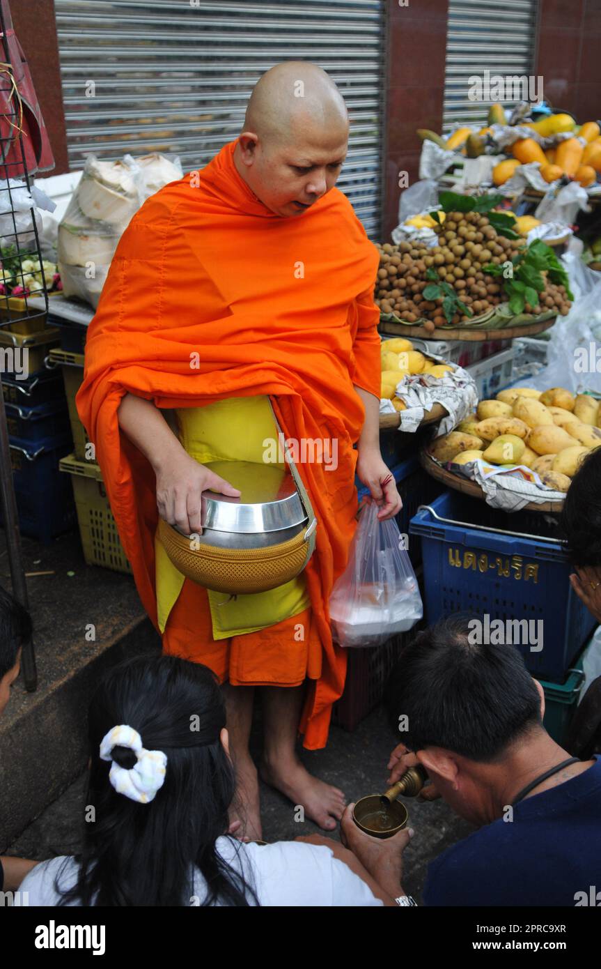 Ein thailändischer buddhistischer Mönch segnet die Einheimischen und empfängt Almosen im Rahmen eines morgendlichen Rituals. Foto in Bangkok, Thailand. Stockfoto