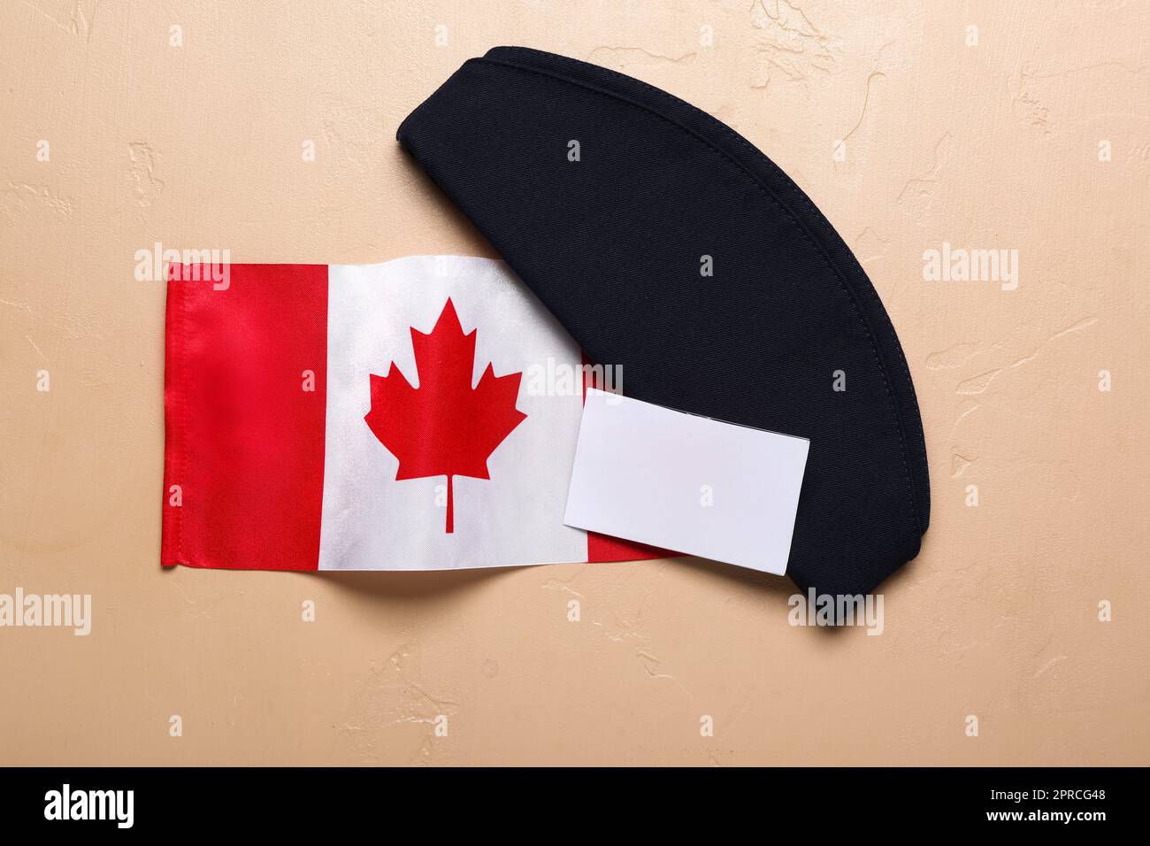 Kanadische Flagge mit Stewardess-Hut und leerem Papier auf beigefarbenem Hintergrund Stockfoto