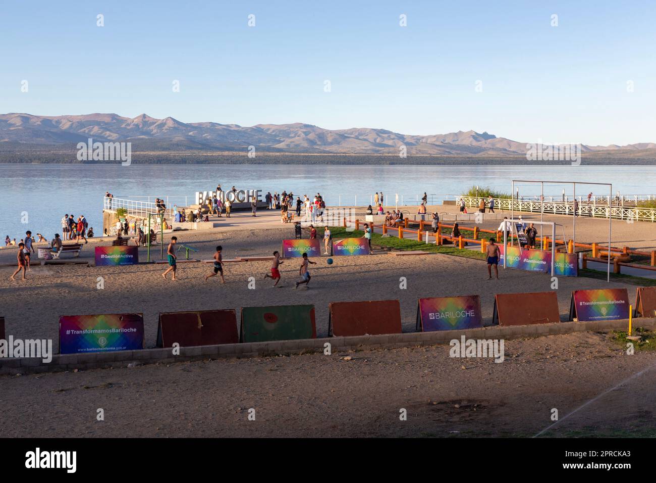 Leute versammeln sich und spielen Football-Spiel an der Nahuel Huapi Lake Beach Waterfront. Sonniger Tag in San Carlos De Bariloche, Patagonien Argentinien Stockfoto