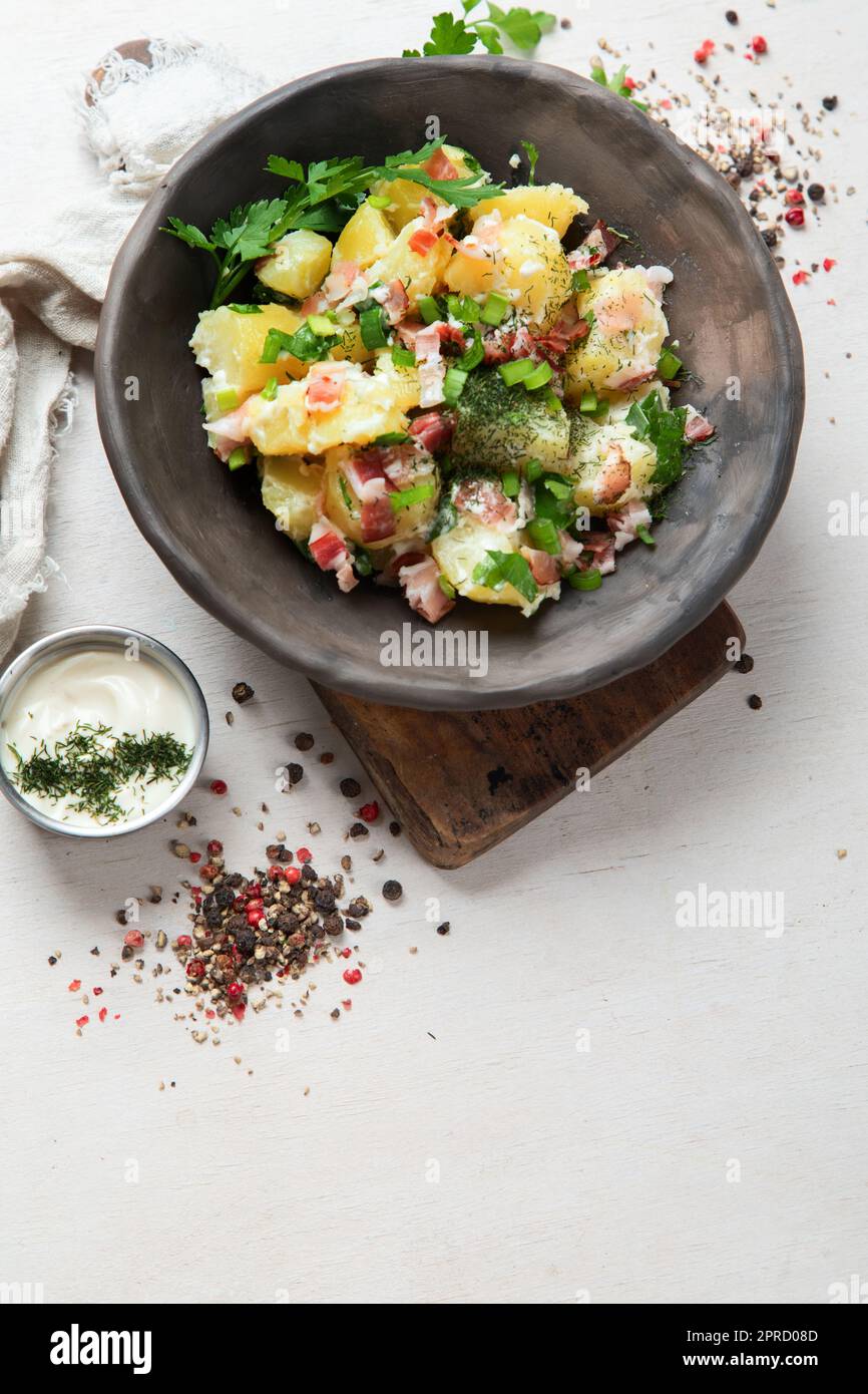 Schüssel mit warmem Kartoffelsalat mit Speck auf weißem Hintergrund. Draufsicht. Stockfoto
