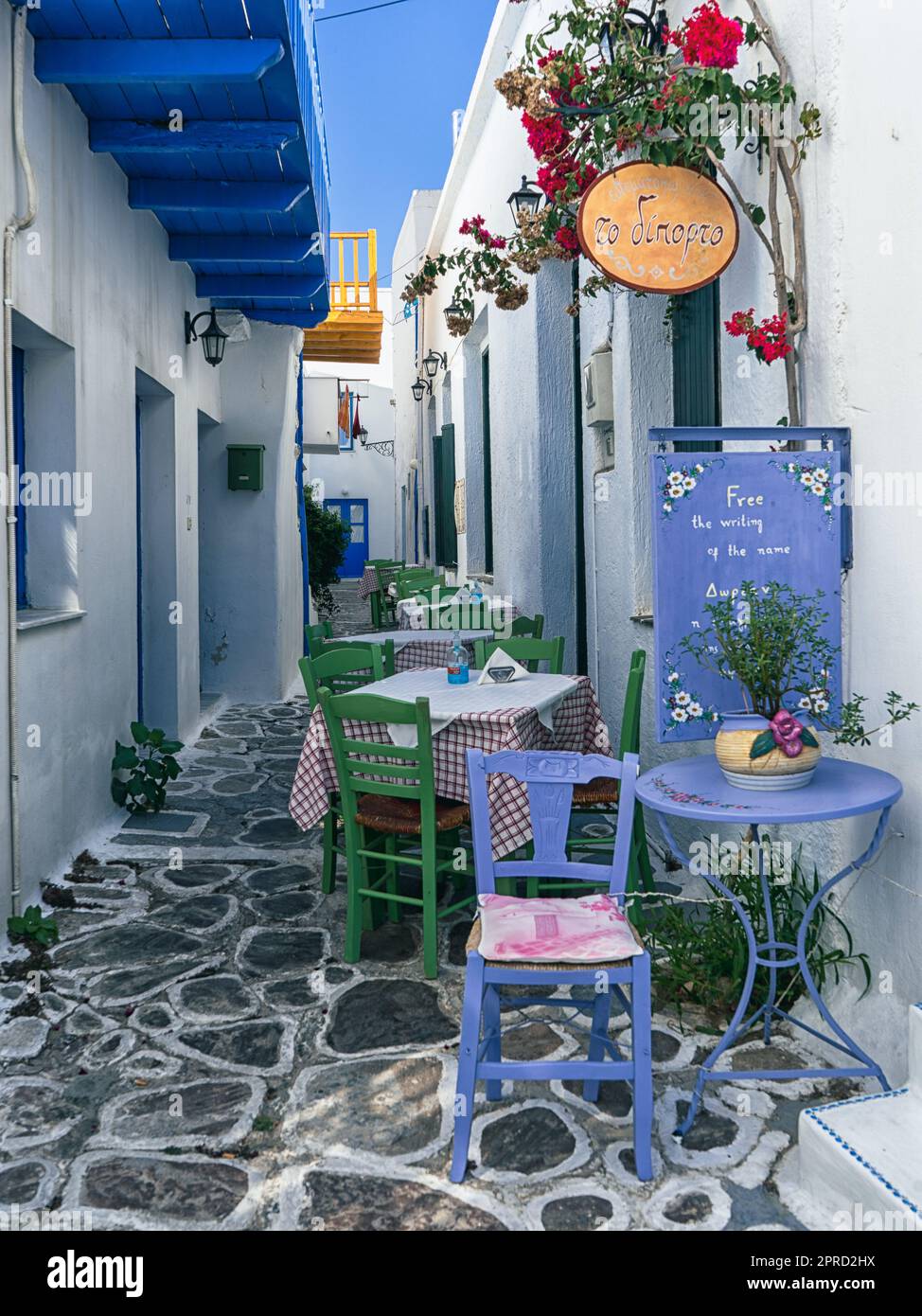 Ein typisch griechisches Restaurant in einer gepflasterten Straße mit weiß getünchten Gebäuden und hellen mediterranen Farben auf der Insel Milos, Griechenland Stockfoto