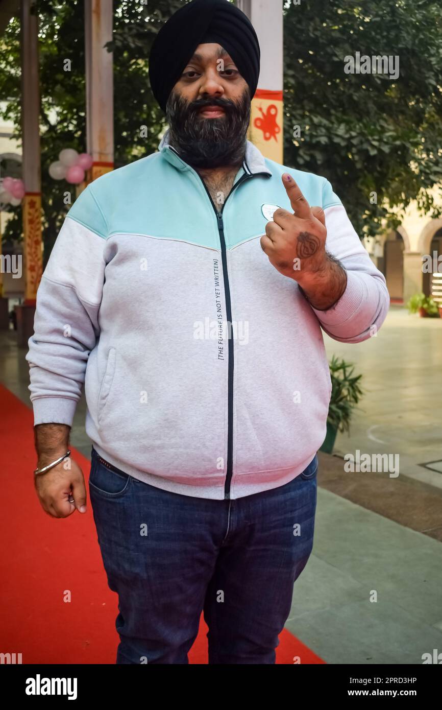 Neu-Delhi, Indien - Dezember 04 2022 - Unbekannte zeigen ihre mit Tinte markierten Finger, nachdem sie vor dem Wahlstand von Ost-Delhi Stimmen abgegeben haben Stockfoto