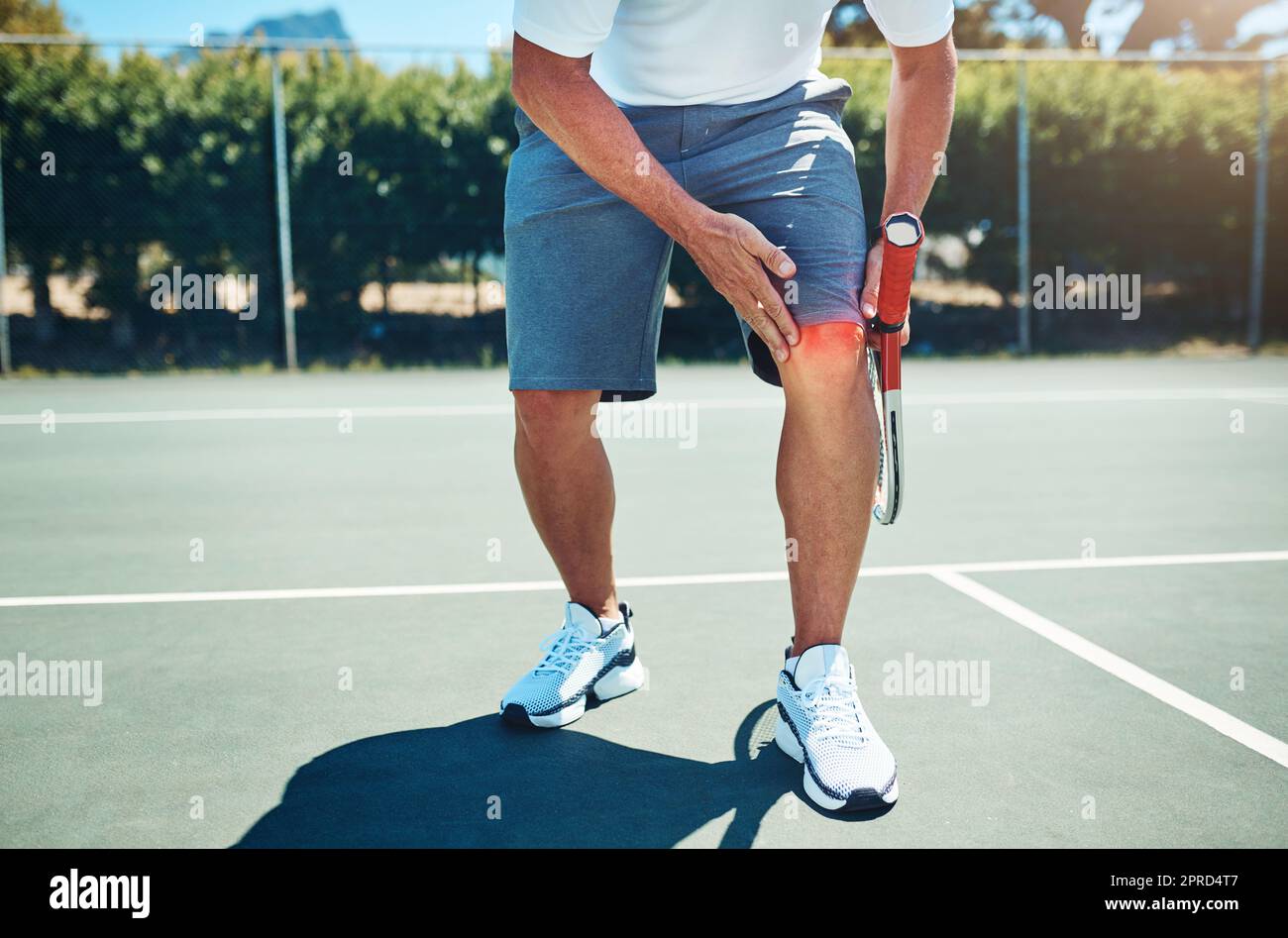 OW My Knee. Ein nicht erkennbarer Sportler, der an einer Knieverletzung leidet, während er alleine Tennis spielt. Stockfoto