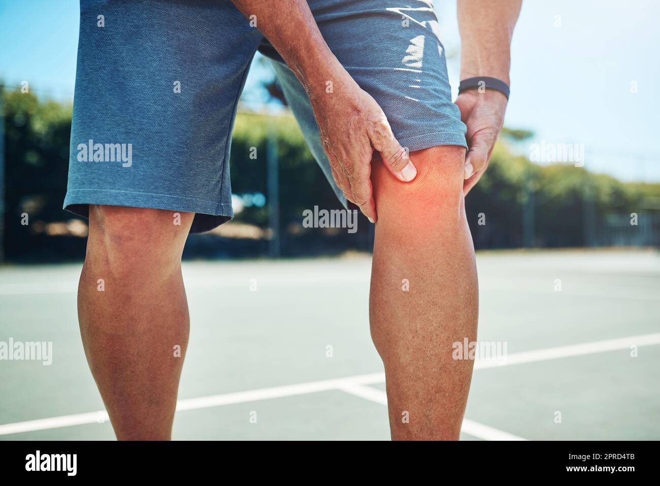 Ich habe mich verletzt. Ein nicht erkennbarer Sportler, der an einer Knieverletzung leidet, während er alleine Tennis spielt. Stockfoto