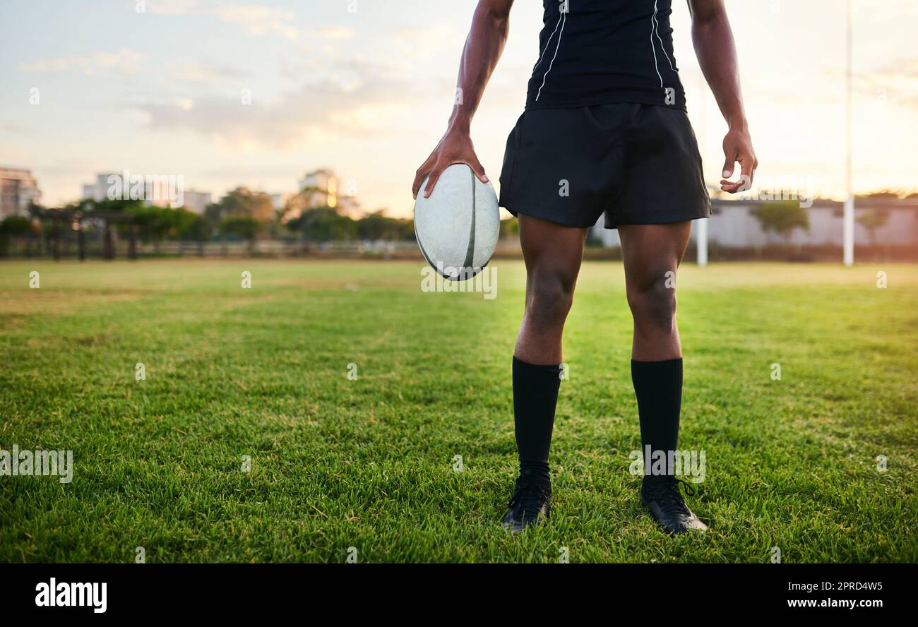 Nichts kann mich aufhalten. Ein nicht erkennbarer Sportler, der alleine steht und während eines morgendlichen Trainings einen Rugby-Ball hält. Stockfoto
