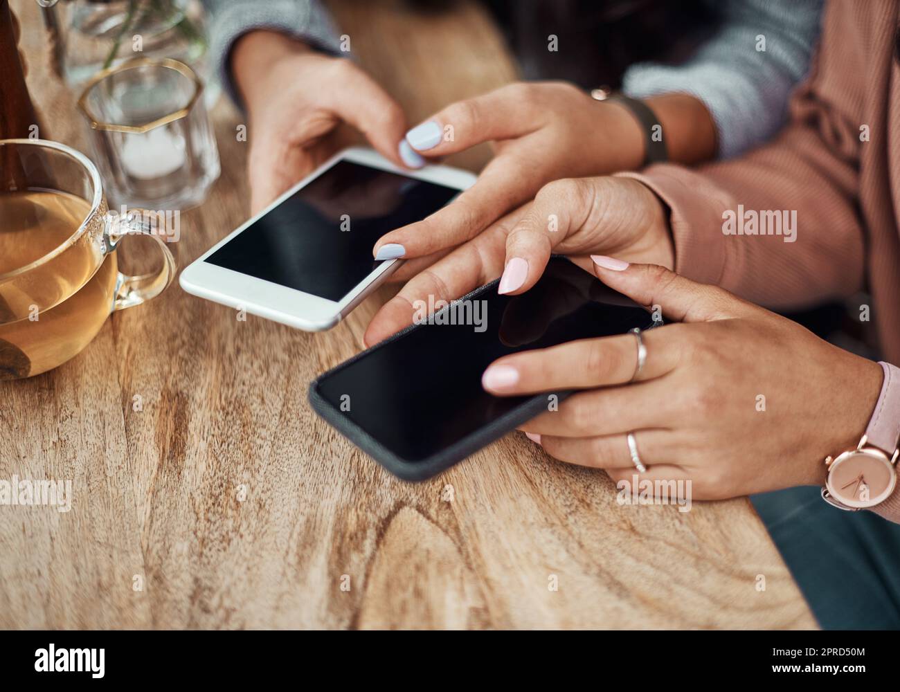 Gehen Sie überall hin, wo das WLAN ist. Zwei Frauen benutzen ihre Smartphones in einem Café. Stockfoto