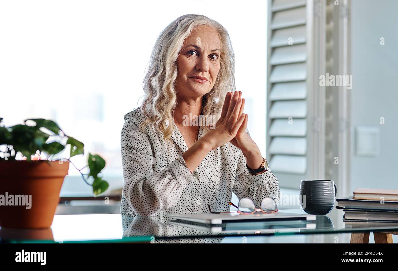 Als Geschäftsfrau muss ich weiterarbeiten. Verkürztes Porträt einer attraktiven Geschäftsfrau, die mit aneinander gereihten Händen von zu Hause aus arbeitet. Stockfoto