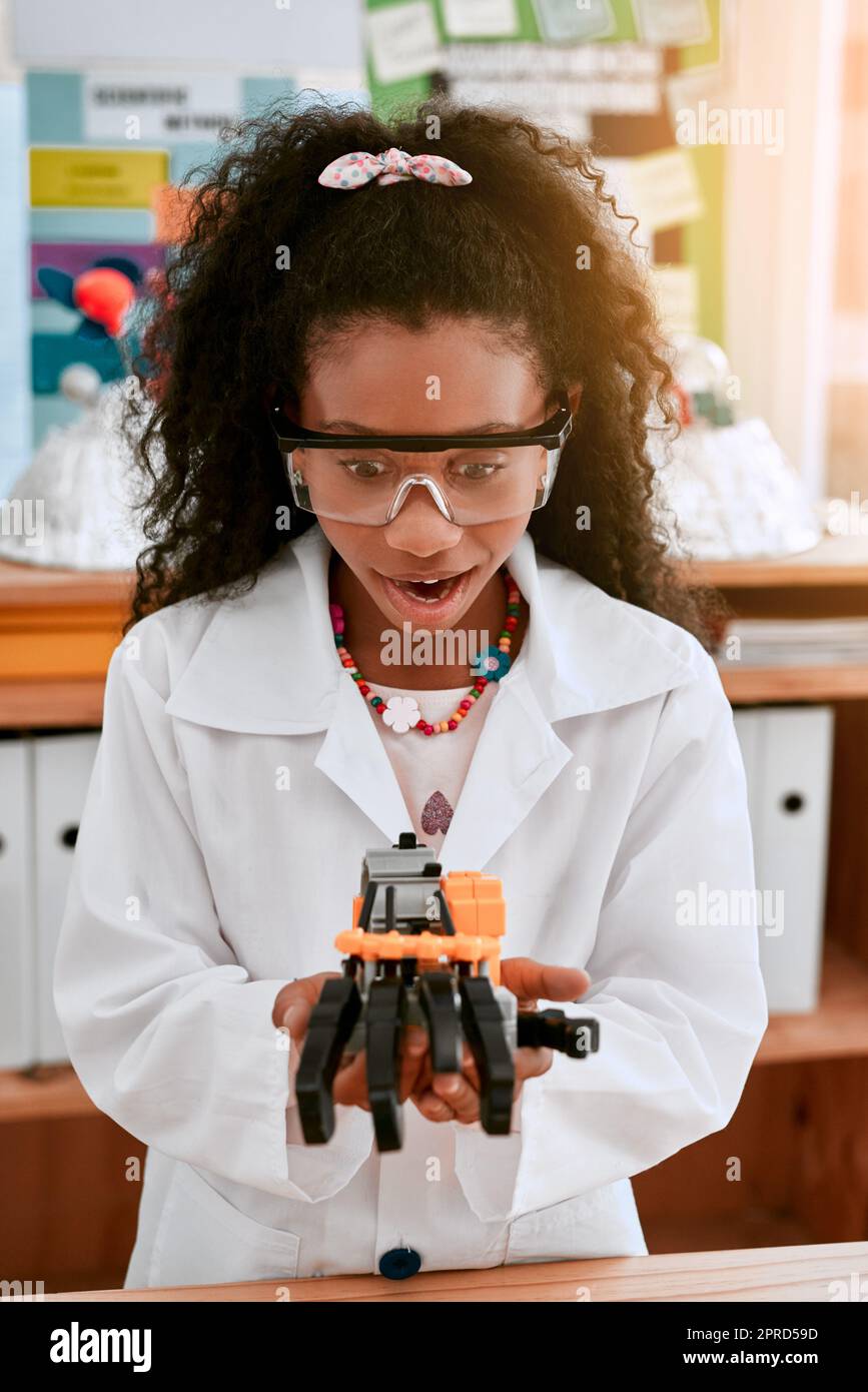 Die Zukunft gehört den Neugierigen. Ein entzückendes kleines Mädchen, das in der Schule einen Roboter baut. Stockfoto
