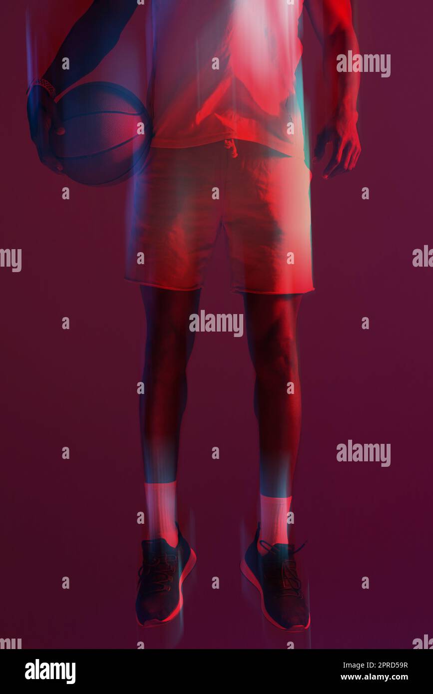 Bereit, es auf die nächste Stufe zu bringen. Rot gefilterte Aufnahme eines nicht erkennbaren Sportlers, der mit einem Basketball im Studio posiert. Stockfoto