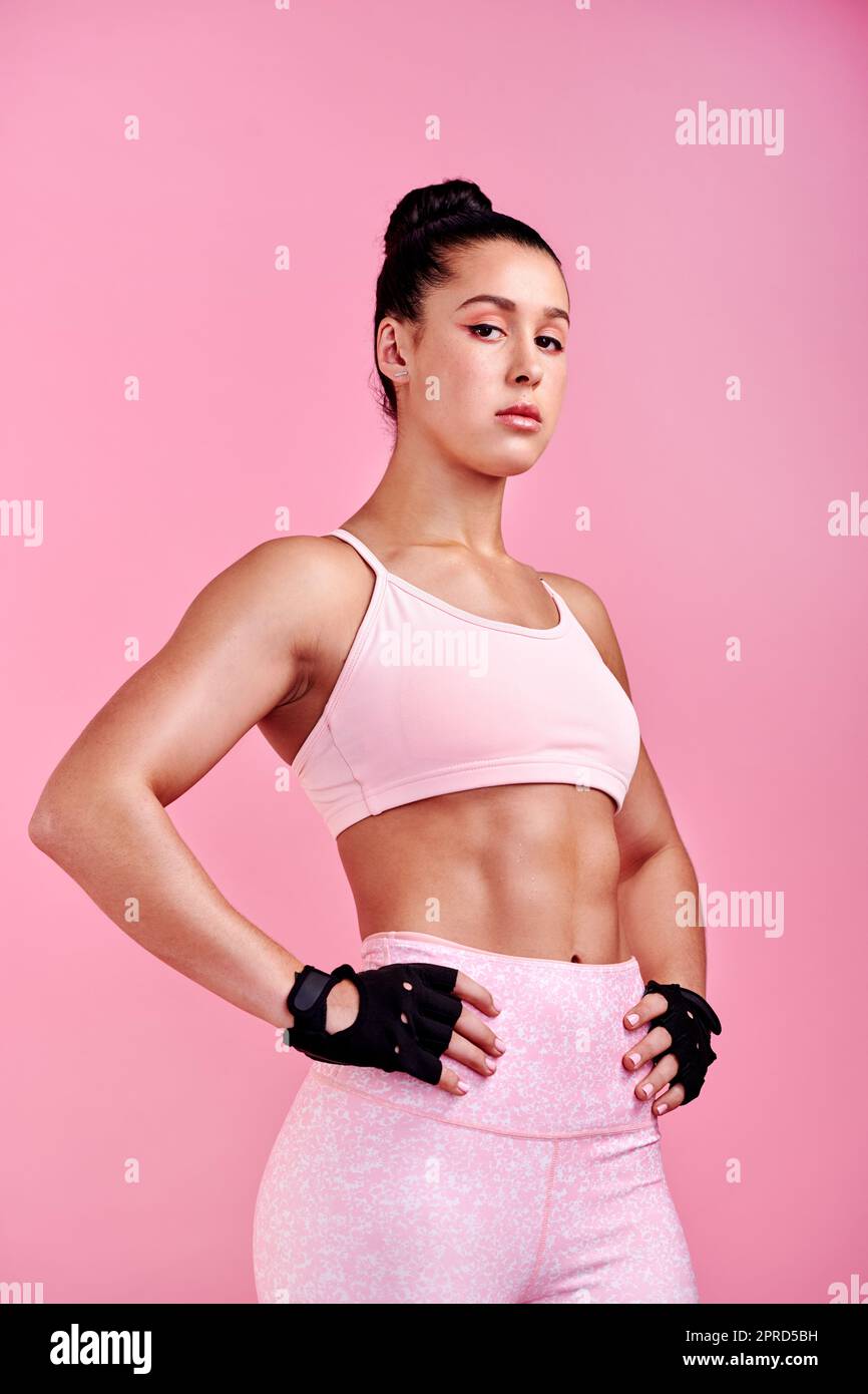 Shes heftig und das ist ihre Schönheit. Studioportrait einer sportlichen jungen Frau, die mit den Händen auf der Hüfte vor einem rosa Hintergrund posiert. Stockfoto