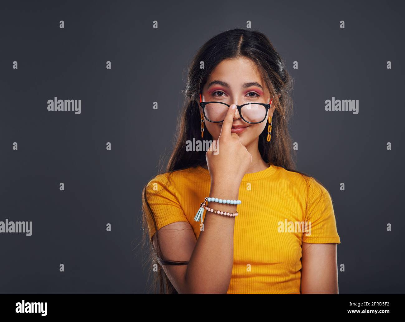 Wir nennen es Mode. Ein Porträt eines attraktiven Teenagers, das eine Brille trägt und allein im Studio vor einem dunklen Hintergrund steht. Stockfoto