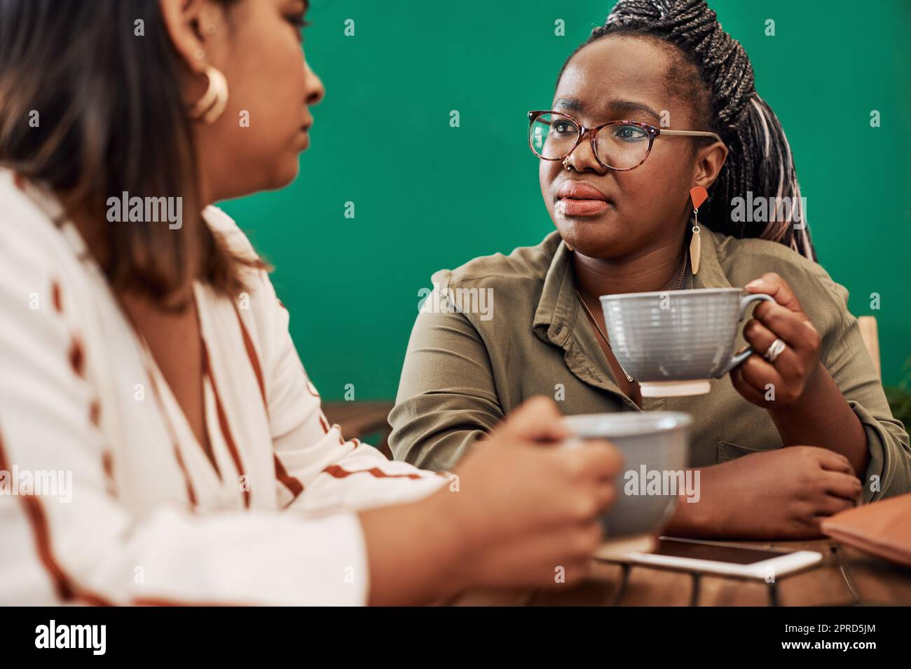 Vergessen Sie nicht, mit Ihren Freunden einzuchecken. Zwei junge Frauen unterhalten sich in einem Café. Stockfoto