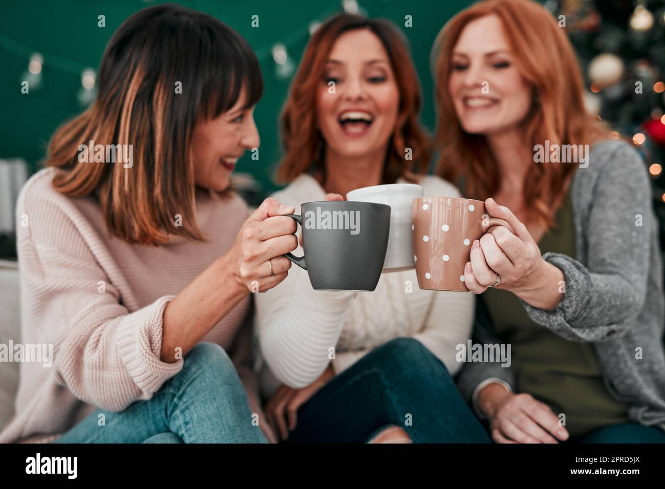 Zu einem Leben voller Erinnerungen. Drei attraktive Frauen, die zu Hause einen Kaffee auf dem Sofa trinken. Stockfoto